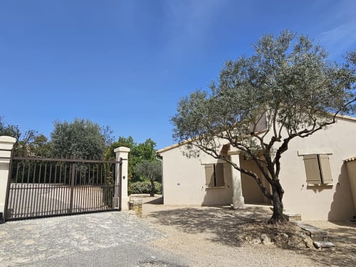 Beige stone house with gated entrance and olive tree in Gordes, France