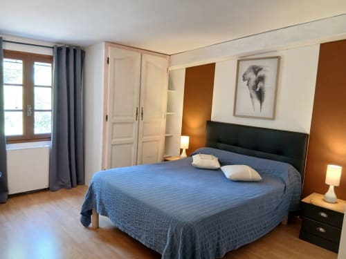 Chambre double spacieuse au Mas D'Alivon à Arles avec literie bleue, penderie, vue sur le jardin et équipements modernes