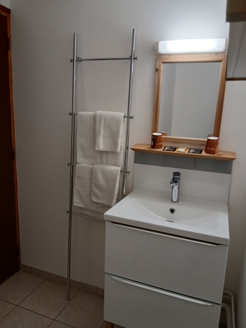 Salle de bain moderne au Mas d'Alivon à Arles avec lavabo blanc, miroir, porte-serviettes et équipements de douche