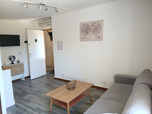 Studio Familial au Mas d'Alivon à Arles : canapé, table en bois, kitchenette et mappemonde murale