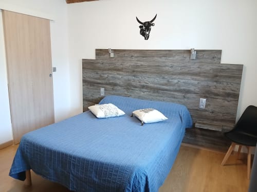 Chambre moderne au Mas D Alivon BnB à Arles avec literie bleue, tête de lit en bois rustique et art taurin
