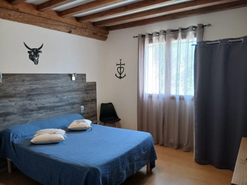 Chambre double au Mas d'Alivon B&B à Arles avec literie bleue, poutres en bois et décor nautique