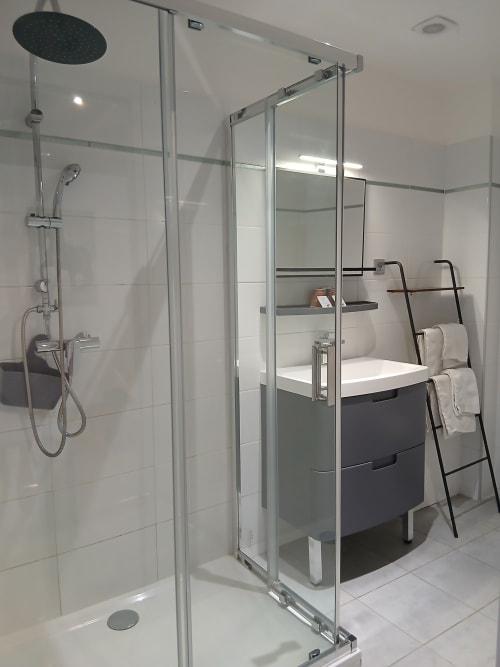 Salle de bain moderne au Mas d'Alivon avec douche vitrée, vasque sombre et échelle porte-serviettes à Arles