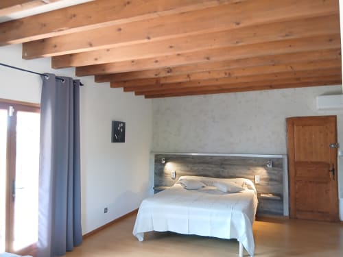 Spacieuse chambre familiale au Mas D Alivon à Arles avec poutres apparentes, lit moderne et accès au balcon