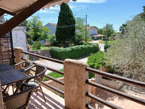 Vue de balcon au Mas d'Alivon à Arles avec fauteuils en osier, cyprès et paysage villageois