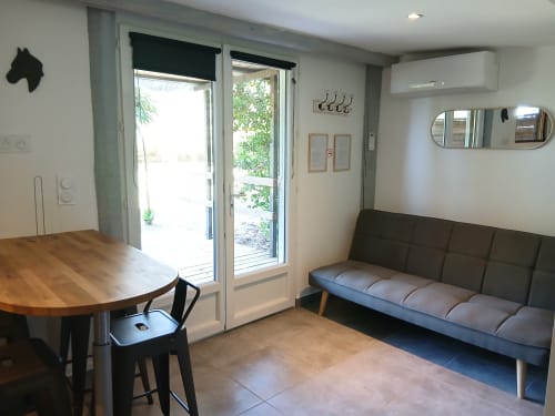 Chambre moderne au Mas d'Alivon à Arles avec table à manger, canapé gris et portes vitrées donnant sur le jardin