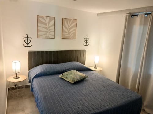 Chambre douillette à la Cabane 2 du Mas D'Alivon B&B à Arles avec lit matelassé bleu, tête de lit verte et décoration marine.