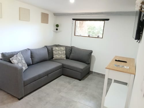 Séjour moderne à la Cabane 2 du Mas D Alivon B&B à Arles avec canapé gris, table en bois et fenêtre