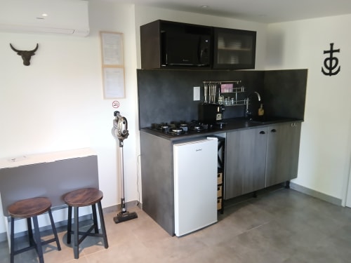 Kitchenette moderne avec cuisinière, plan de travail noir, réfrigérateur blanc et coin bar dans la chambre Mas D Alivon BnB, Arles
