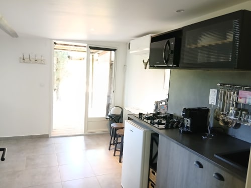 Cuisine moderne avec plan de travail noir, cuisinière à gaz et micro-ondes au Mas D'Alivon B&B à Arles