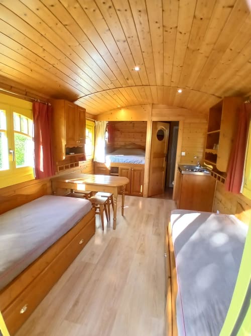 Intérieur en bois de la Roulotte au Mas D Alivon, Arles - lit, coin repas, kitchenette et rangements