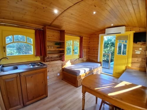 Chambre confortable de roulotte au Mas D Alivon à Arles : intérieur bois, lit, kitchenette et touches jaunes