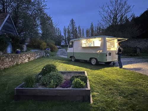 Vieux food truck du Gîte Sous Le Phare à Louannec, illuminé au crépuscule avec jardins entretenus