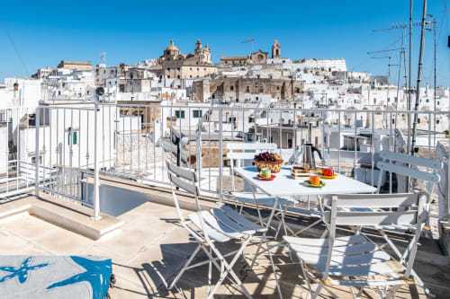 Terrazza panoramica di Pietra & Luce a Ostuni con tavolo da pranzo con vista sui caratteristici edifici biancastri e il mare