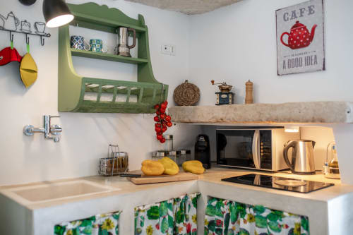 Affascinante cucina nell'appartamento B&B Pietra & Luce a Ostuni con scaffali verdi, limoni e decori costieri