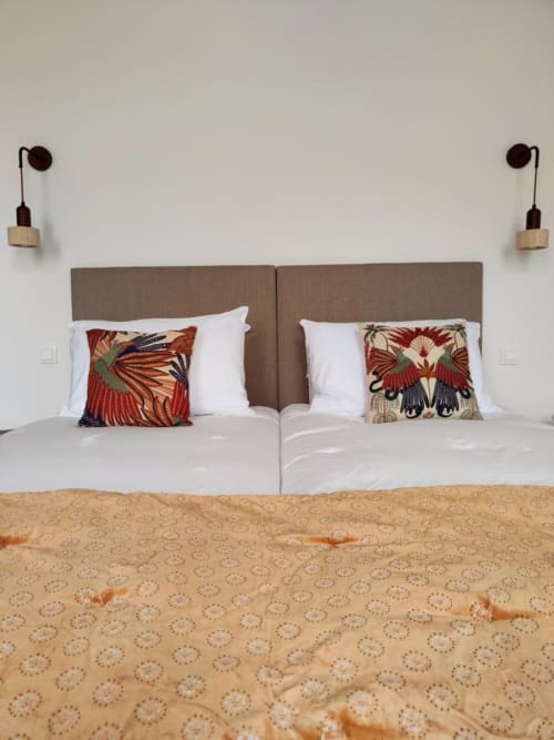 Lits jumeaux aux têtes de lit taupe, oreillers rouges à motifs d'oiseaux et couvre-lit beige dans la chambre Olympe au Rêve d'Alice, Saint-Puy
