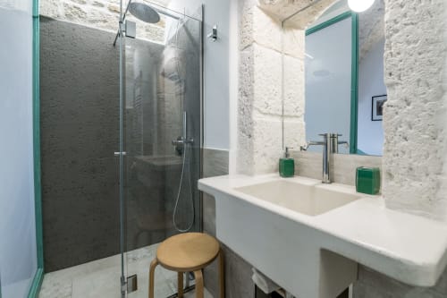 Bagno moderno nell'appartamento Pietra & Luce, Ostuni con muri in pietra, specchio con cornice verde e doccia in vetro
