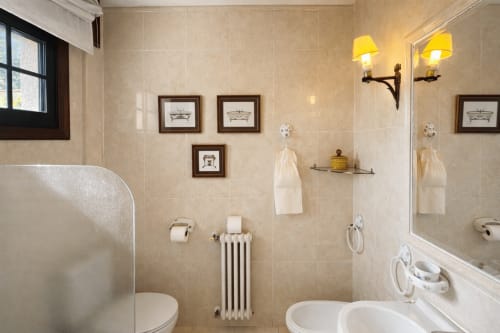 Baño elegante en villa Holibai con azulejos beige, doble lavamanos, cuadros y apliques amarillos