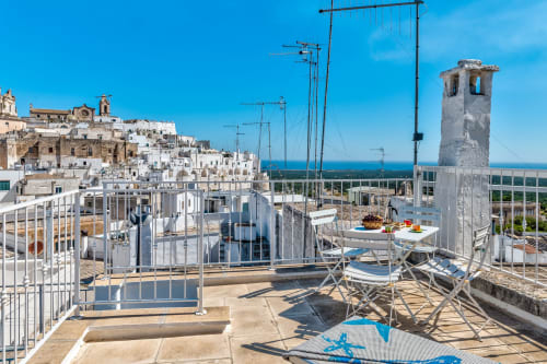 Terrazza panoramica di Pietra & Luce a Ostuni con vista mare, edifici imbiancati e zona pranzo
