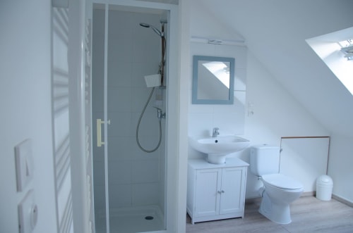 Salle de bain moderne au Relais de Poste des Relais-Orbigny avec douche à l'italienne, lavabo, toilettes et miroir encadré bleu