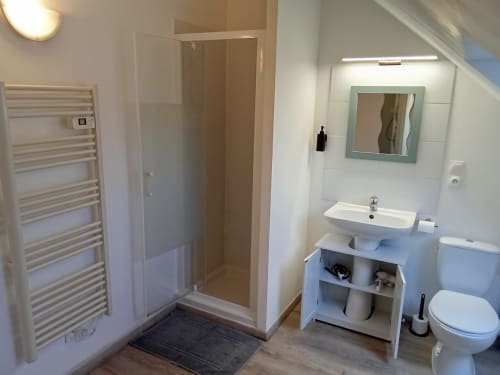 Salle de bains moderne aux Relais-Orbigny avec douche, vasque, toilettes, sèche-serviettes chauffant et miroir éclairé