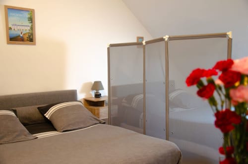 Chambre aux Relais-Orbigny avec lit à baldaquin, fleurs rouges et vue sur le jardin à Orbigny, France