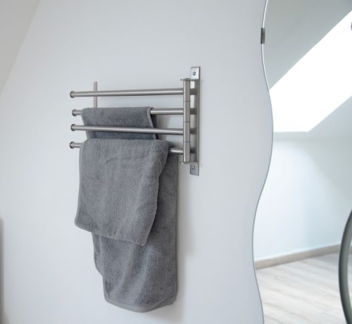 Porte-serviettes en acier inoxydable avec serviettes grises fixé sur mur blanc de la salle de bain aux Relais-Orbigny