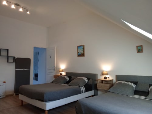 Chambre moderne aux Relais-Orbigny avec deux lits, lampes de chevet et plafond mansardé avec lucarne à Orbigny, France