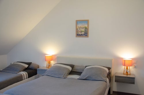 Chambre douillette aux Relais-Orbigny à Orbigny avec lits jumeaux, lampes orange et affiche de Loches sous plafond mansardé