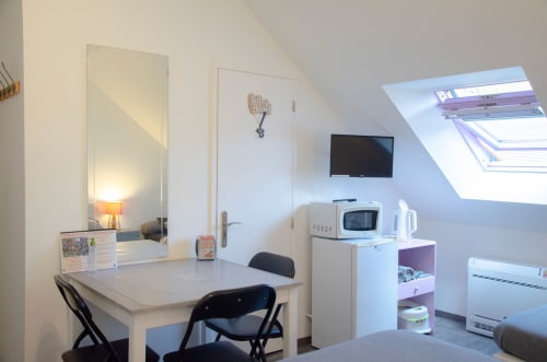 Chambre mansardée aux Relais-Orbigny avec bureau, TV, kitchenette avec micro-ondes et fenêtre de toit offrant une vue sur le jardin, Orbigny