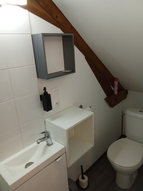 Salle de bains moderne du Relais de Jeanne aux Relais-Orbigny, carrelage blanc, lavabo, toilettes et poutre bois