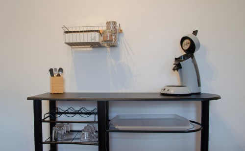 Comptoir de cuisine noir avec porte-ustensiles en bois, lampe de bureau et étagères murales aux Relais-Orbigny