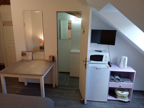 Chambre moderne à l'étage des Relais-Orbigny avec kitchenette, TV, salle de bain et décor blanc à Orbigny