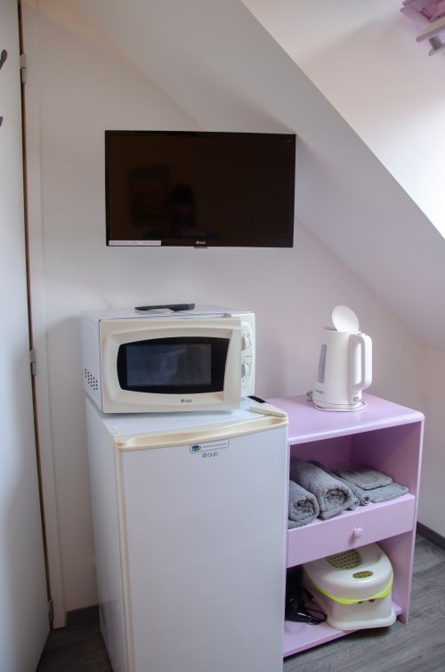 Kitchenette équipée dans la chambre d'hôte Les Relais-Orbigny : micro-ondes, réfrigérateur, bouilloire électrique et TV murale