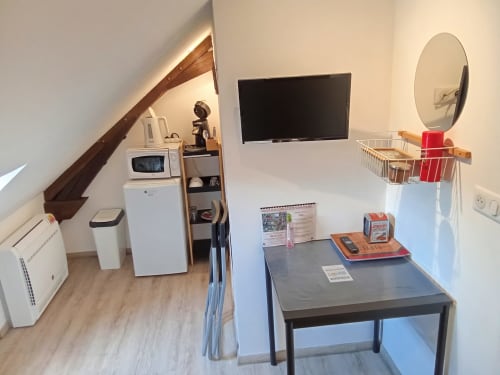 Chambre mansardée chaleureuse aux Relais-Orbigny avec TV, micro-ondes, réfrigérateur, bureau et miroir ovale à Orbigny