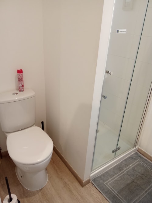 Salle de bain moderne aux Relais-Orbigny avec toilettes, douche vitrée et parquet