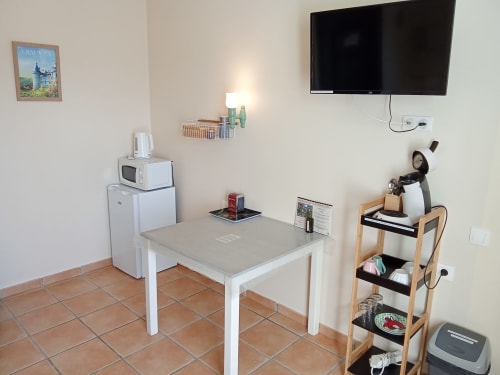 Kitchenette du Relais du Jardin avec table à manger, TV, réfrigérateur et micro-ondes aux Relais-Orbigny BnB