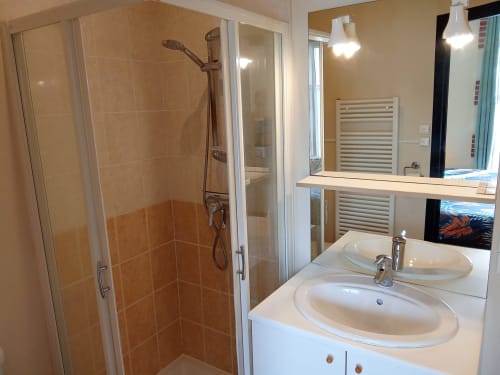 Salle de bain moderne aux Relais-Orbigny avec double vasque, douche vitrée, sèche-serviettes chauffant et miroir au Relais du Jardin
