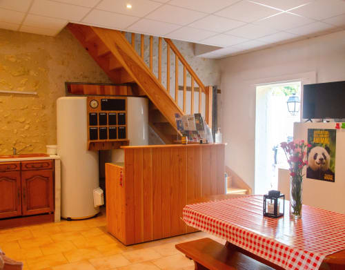 Coin repas chaleureux aux Relais-Orbigny avec escalier en bois, nappe à carreaux rouges et décor rustique.