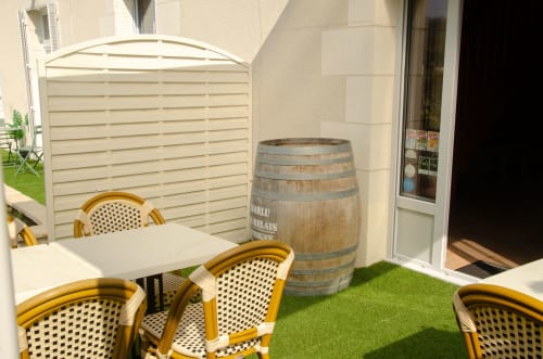 Terrasse extérieure des Relais-Orbigny avec chaises de bistrot, tonneau de vin et clôture de confidentialité crème à Orbigny, France