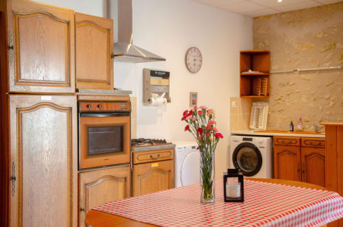 Cuisine vintage aux Relais-Orbigny avec meubles en bois, table à carreaux rouges et fleurs fraîches