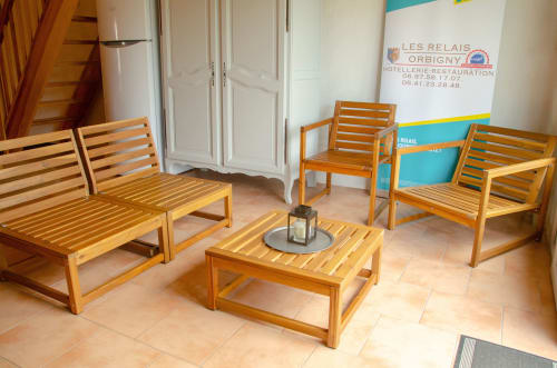Espace de détente en bois à l'hôtel Les Relais-Orbigny avec fauteuils, banquette et table basse sur sol en carrelage terre cuite