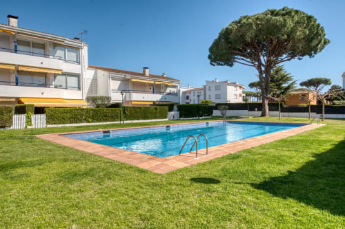 Piscina amb terrassa de teula a Finques Garcia Enrich a Palafrugell, envoltada de jardins manicurats i paisatge mediterrani