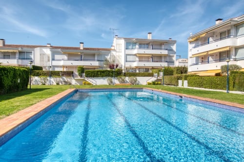 Piscina de mida olímpica al complex residencial Finques Garcia Enrich a Palafrugell, Espanya, amb edificis residencials i