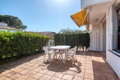 Terrassa assolellada amb taula de menjador a l'hotel Finques Garcia Enrich de Palafrugell, amb para-sol groc i tanques verdes