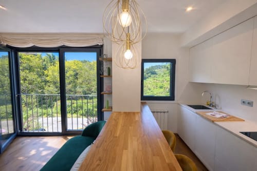 Cocina-comedor moderno con mesa de madera, vistas a la montaña y acceso a balcón en apartamento de Baiona