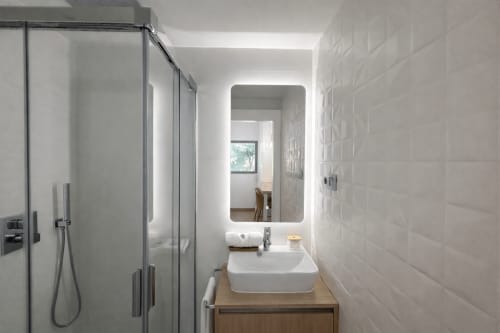 Baño moderno del apartamento Holibai Baiona con ducha abierta, espejo iluminado y tocador de madera