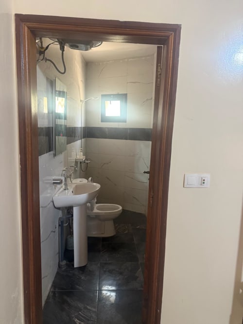 Salle de bains de l'hôtel Keur Medzo Lac Rose à Niaga avec lavabo sur colonne, toilettes et douche carrelée