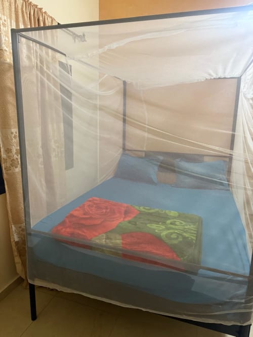 Chambre Bandia à Keur Medzo Lac Rose avec lit à moustiquaire, matelas bleu et literie rouge-vert à Niaga, Sénégal