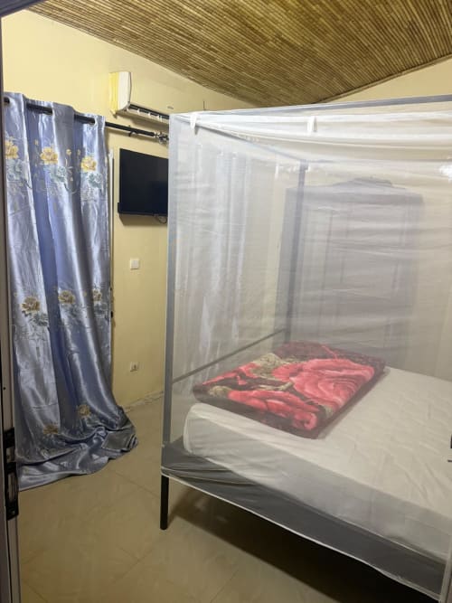 Chambre avec lit à moustiquaire et linge de lit rouge à l'hôtel Keur Medzo à Lac Rose, Sénégal
